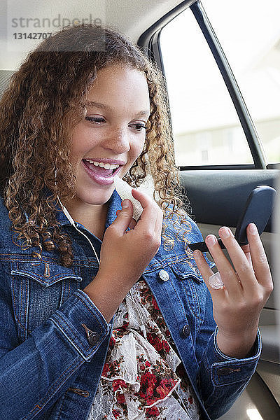 Teenager trägt Lippenbalsam auf  während er im Auto sitzt