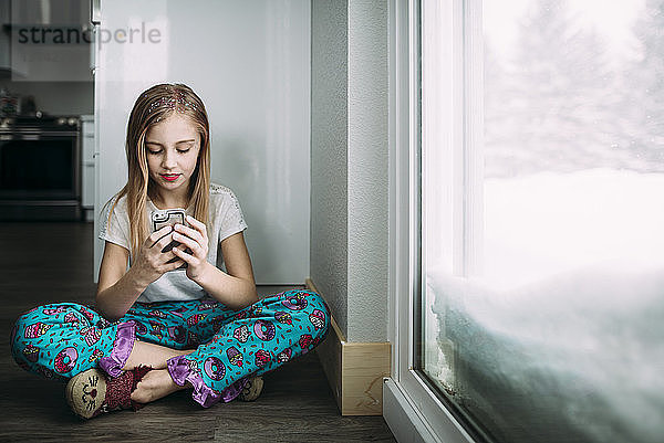 Mädchen in voller Länge benutzt zu Hause ein Mobiltelefon