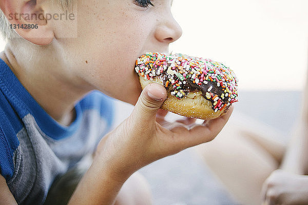 Ausgeschnittenes Bild eines Jungen  der Donut isst