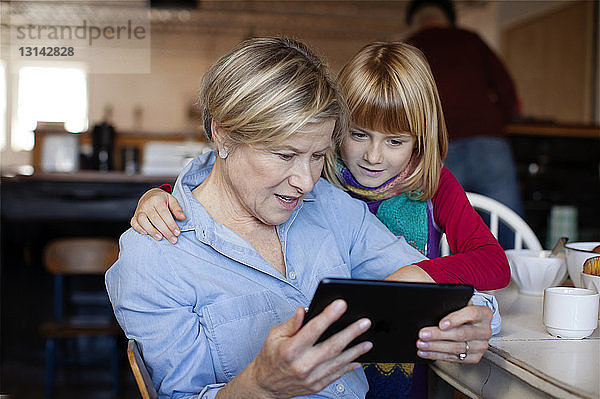 Großmutter und Enkelin schauen auf Tablet-Computer