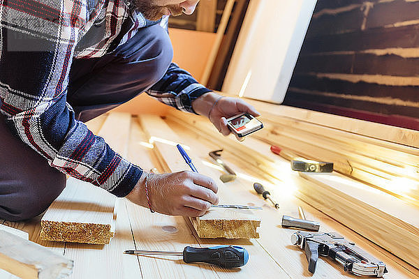 Mitschnitt eines Tischlers  der während der Arbeit in der Werkstatt per Telefon fotografiert