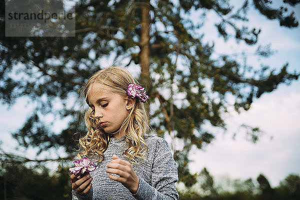 Mädchen mit Blumen an Bäumen stehend