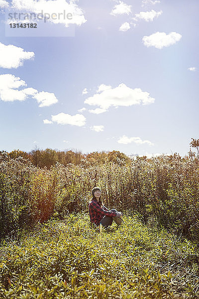 Entspannte Frau sitzt im Sommer auf dem Feld