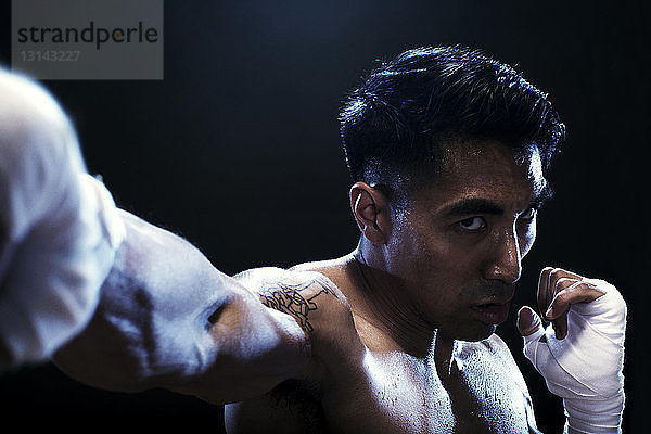 Porträt einer entschlossenen Kickboxerin  die vor schwarzem Hintergrund trainiert