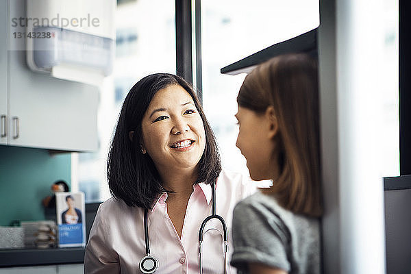 Lächelnde Ärztin misst in der Klinik die Grösse eines Mädchens