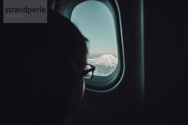 Ausgeschnittenes Bild eines Kindes  das durch ein Flugzeugfenster schaut