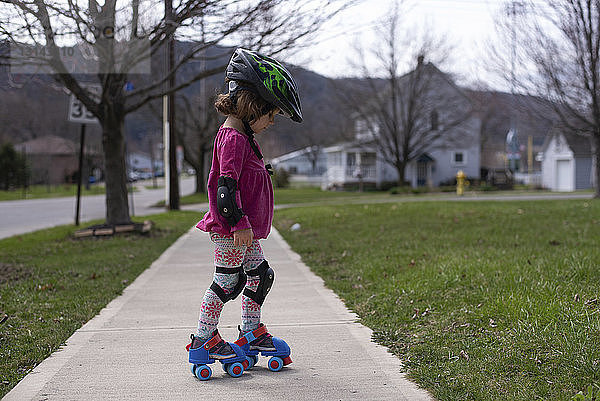 Seitenansicht eines Mädchens beim Rollschuhlaufen auf einem Fußweg im Park