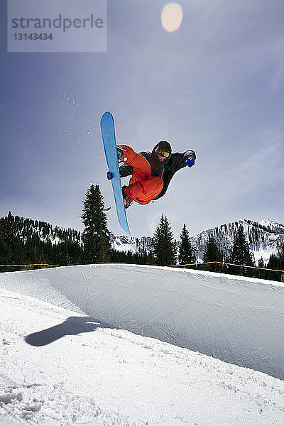 Mann beim Snowboarden auf Berg gegen Himmel