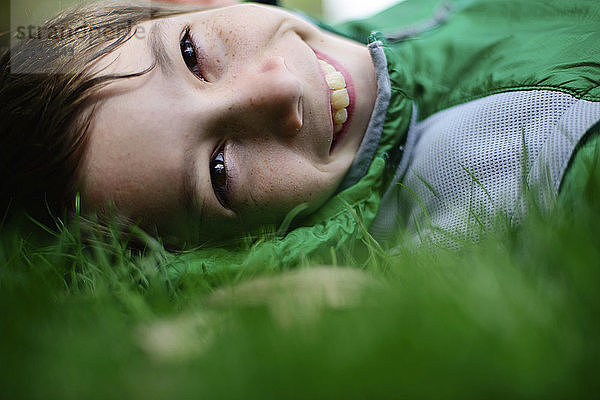 Porträt eines glücklichen Jungen auf einem Grasfeld liegend