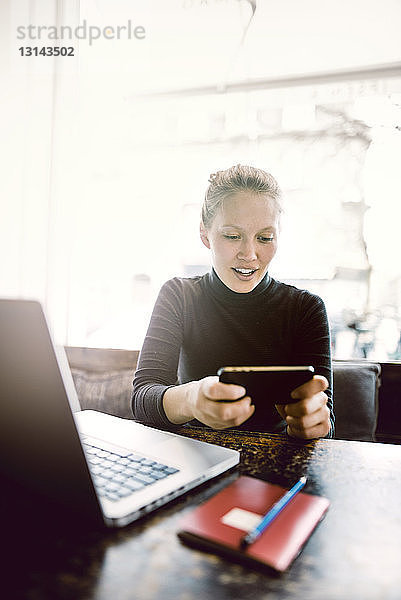 Junge Frau benutzt Smartphone im Café