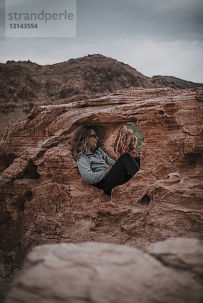 Wanderer entspannt sich in Felsformation gegen den Himmel im Red Rock Canyon National Conservation Area