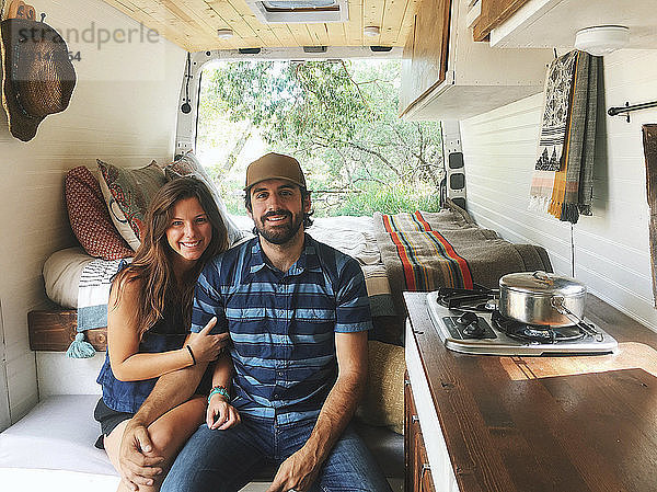Porträt eines glücklichen Paares auf einem Sitz im Wohnmobil im Wald