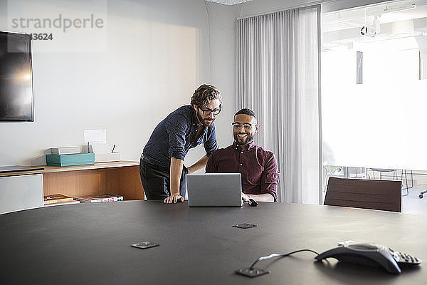 Männliche Mitarbeiter diskutieren bei Besprechung im Sitzungssaal