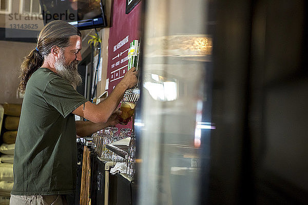 Seitenansicht des Barkeepers  der Bier aus dem Zapfhahn ausschenkt