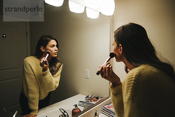 Frau trägt Make-up auf und reflektiert auf Spiegel