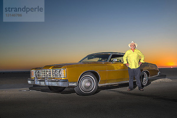 Porträt eines älteren Mannes  der neben einem gelben Auto steht