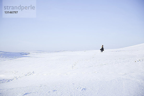 Junges Mädchen geht in verschneiter Landschaft spazieren