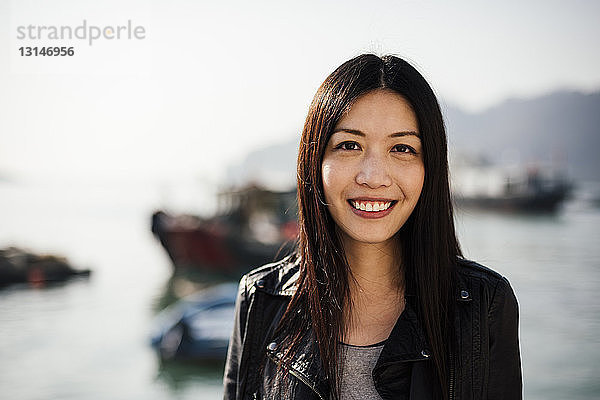 Porträt einer jungen Frau vor einem Boot auf dem Wasser  die lächelnd in die Kamera schaut