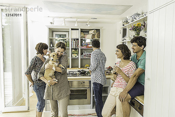 Fünf erwachsene Freunde und ein Hund versammeln sich in der Küche