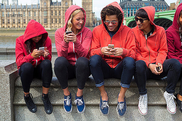 Gruppe junger Menschen mit Blick auf ein Mobiltelefon