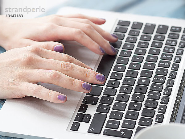 Junge Frau beim Tippen auf der Laptop-Tastatur  Fokus auf die Hände