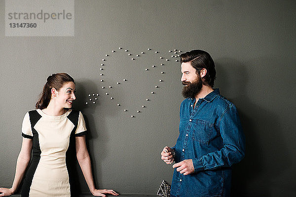 Junges Paar an der Wand mit Herzform