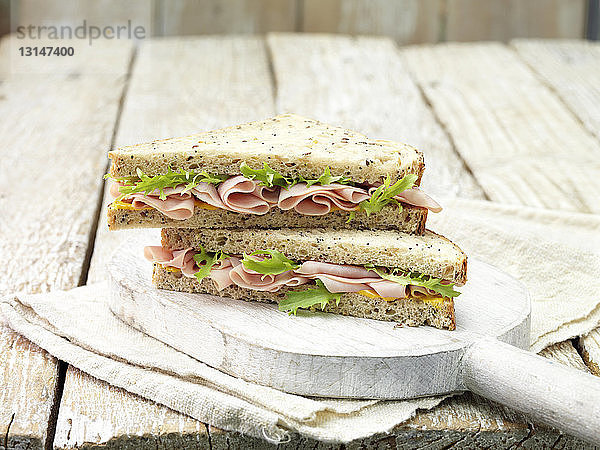 Hauchdünnes Sandwich mit Schinken  Senf und Salatblatt auf geschnittenem Saatbrot