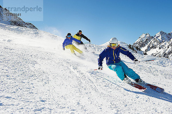 Drei Skifahrer fahren bergab