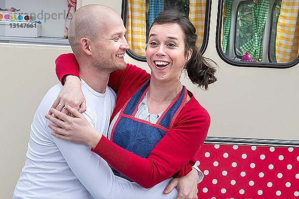 Mid adult couple embracing outside of caravan