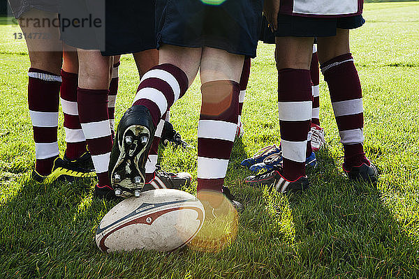 Teenager-Rugbymannschaft  die den Ball aus dem Huddle kickt