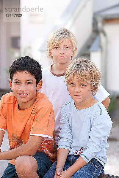 Lächelnde Jungen sitzen im Freien zusammen