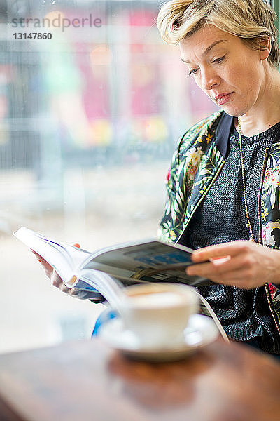 Frau liest Buch in einem Cafe