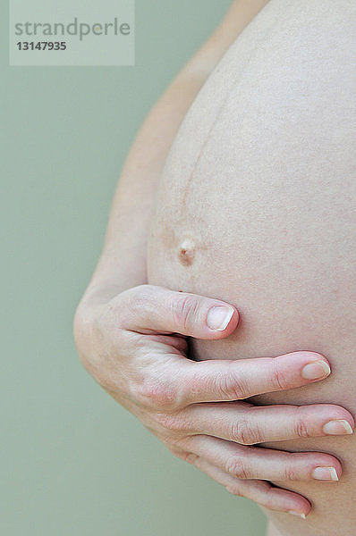 Hand stützt schwangeren Bauch