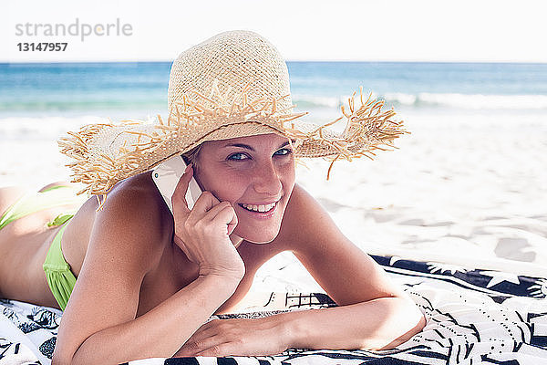 Frau spricht mit Handy am Strand