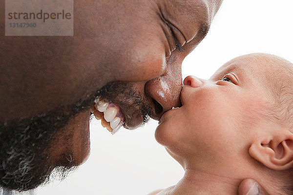 Baby beißt Nase des lachenden Vaters