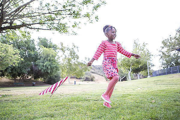 Mädchen mit amerikanischer Flagge spielt im Park