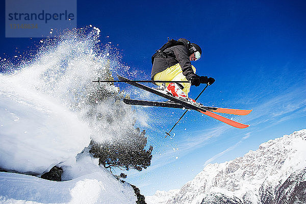 Männlicher Skifahrer mitten in der Luft am Berg
