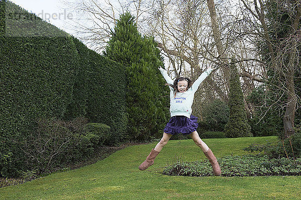 Junges Mädchen springt mitten in der Luft im Garten