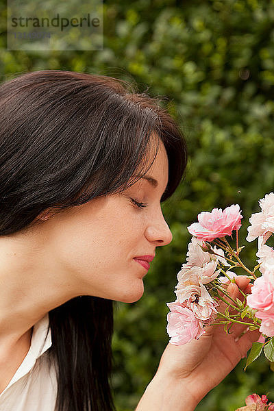 Frau riecht an Blumen im Freien