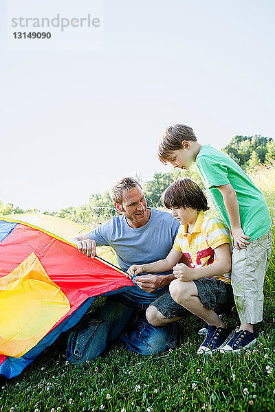 Jungen und Vater bauen Zelt