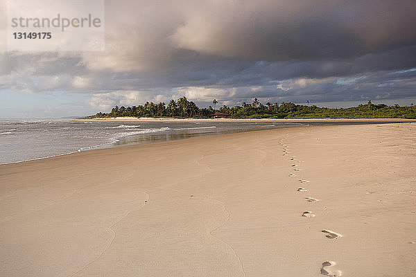 Fußabdrücke am tropischen Strand in der Morgendämmerung