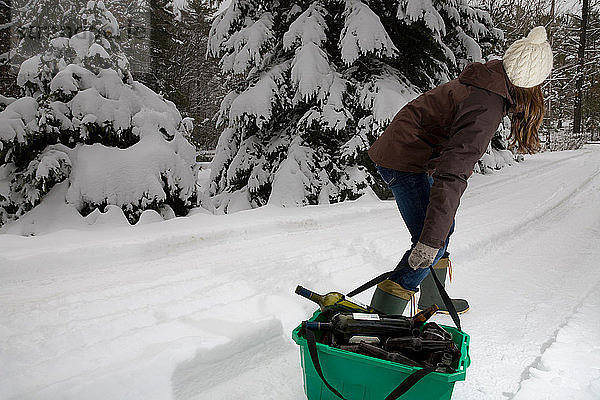 Frau schleppt Recycling im Schnee