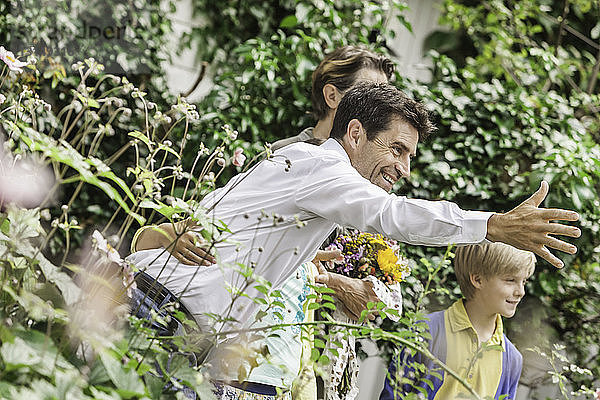 Älteres Paar begrüßt Enkelkinder im Garten