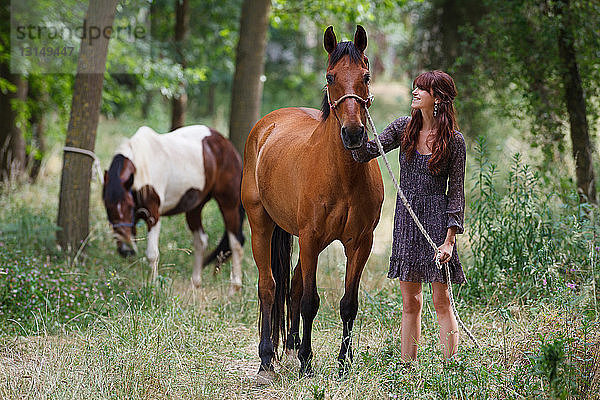 Frau geht mit Pferd im Wald spazieren