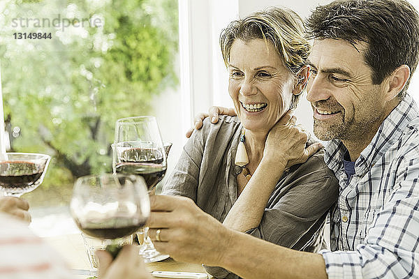 Ehepaar stößt mit Rotwein am Esstisch an