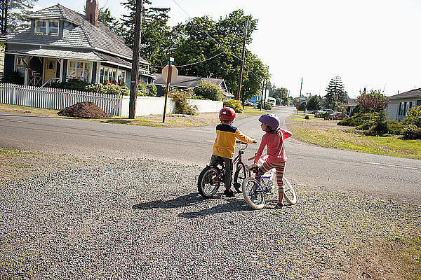 Bruder und Schwester auf Fahrrädern in der Nachbarschaft