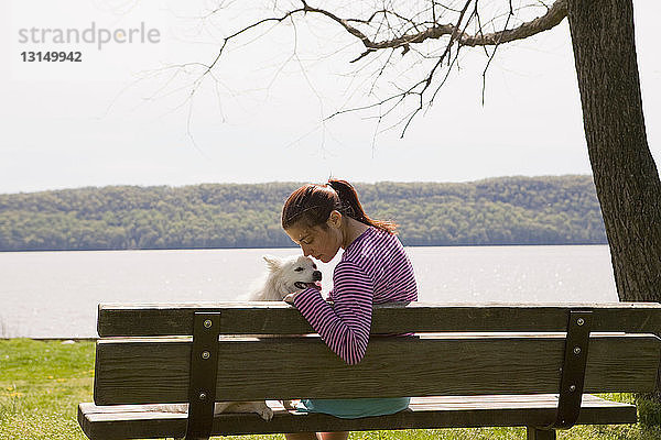 Frau mit Hund auf Parkbank