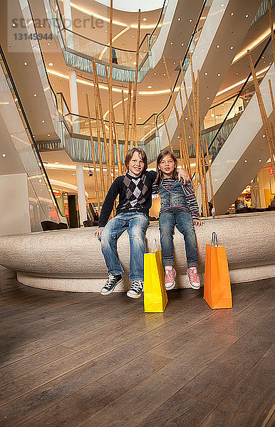 Bruder und Schwester sitzen auf einem Springbrunnen