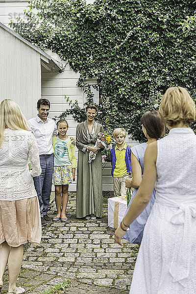 Drei-Generationen-Familie begrüßt sich gegenseitig im Garten mit Geburtstagsgeschenken