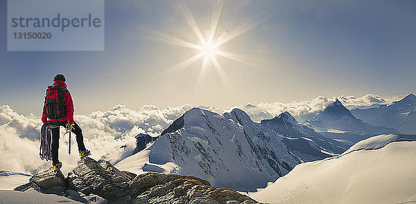 Panoramablick auf einen männlichen Bergsteiger  der von einem schneebedeckten Berggipfel aus blickt  Schweizer Alpen  Schweiz
